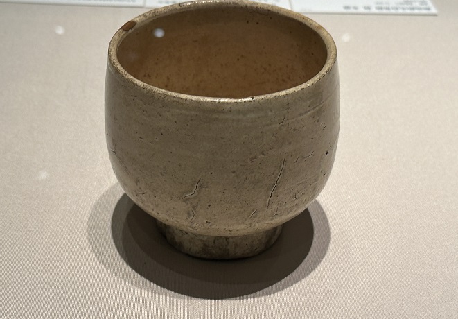 高台が高く、丸みを帯びた独特の器形から、もとは祭器であったと推測されます。灰茶色の胎全体を白土で化粧し、透明釉をかけた「無地刷毛目」の碗で、日本で茶碗として珍重されました。陶芸家浜田庄司(1894〜1978)が激賞したという逸話が残っています。

「冬頭」とは、朝鮮時代の陶磁器である無地刷毛目茶碗の銘です。この茶碗は一般的に、装飾や絵付けが施されておらず、無地の状態で焼かれたものです。無地の茶碗は、その純粋な美しさや素朴さが評価され、茶の湯や茶道の儀式で使用されました。

刷毛目とは、陶器の表面に刷毛のような筋目模様がつけられた技法のことを指します。この技法は朝鮮陶磁器の特徴の一つであり、無地の茶碗に施されることで、質素でありながらも独特な風合いが生まれます。

「冬頭」という銘は、具体的な意味や由来についての情報は限られています。しかし、銘は茶碗に付けられる特定の名前や語句を指すことが多く、その由来や意味は作成時の背景や制作目的に関連している可能性があります。

朝鮮時代の無地刷毛目茶碗は、日常的な茶の飲み物として使われるだけでなく、茶道の儀式や雅趣を楽しむための茶碗としても重要な役割を果たしました。そのため、現在でも無地刷毛目茶碗は美術品や収集品として高く評価され、韓国や他の国の博物館や美術館で展示されています。