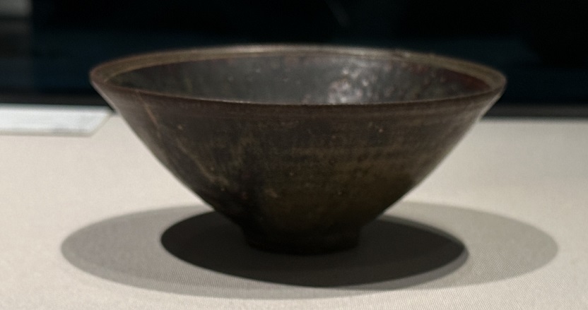 高麗時代の黒釉碗は、12世紀に作られた陶磁器で、その名前の通り黒い釉薬が使われています。この黒釉は、鉄分を含んだ釉薬であり、焼成時の窯の状態によって異なる色調や光沢を持つことが特徴です。 高麗時代の黒釉碗は、一般的に小ぶりなサイズであり、丸みを帯びた形状をしています。茶碗の内側と外側の両方に黒釉が施されており、その表面は光沢があり滑らかです。黒釉の色調は濃淡があり、窯の焼成状態によって異なる黒の表現が生まれます。 黒釉碗は、茶の湯や茶道の儀式において使用されることがありました。その深みのある色合いや光沢は、雅趣を追求する茶の湯の世界において高く評価されました。また、黒釉碗は日常的な食器としても使用され、高麗時代の人々の生活において重要な役割を果たしました。 現在、高麗時代の黒釉碗は美術品や収集品として高い評価を受けており、韓国や他の国の博物館や美術館で展示されています。